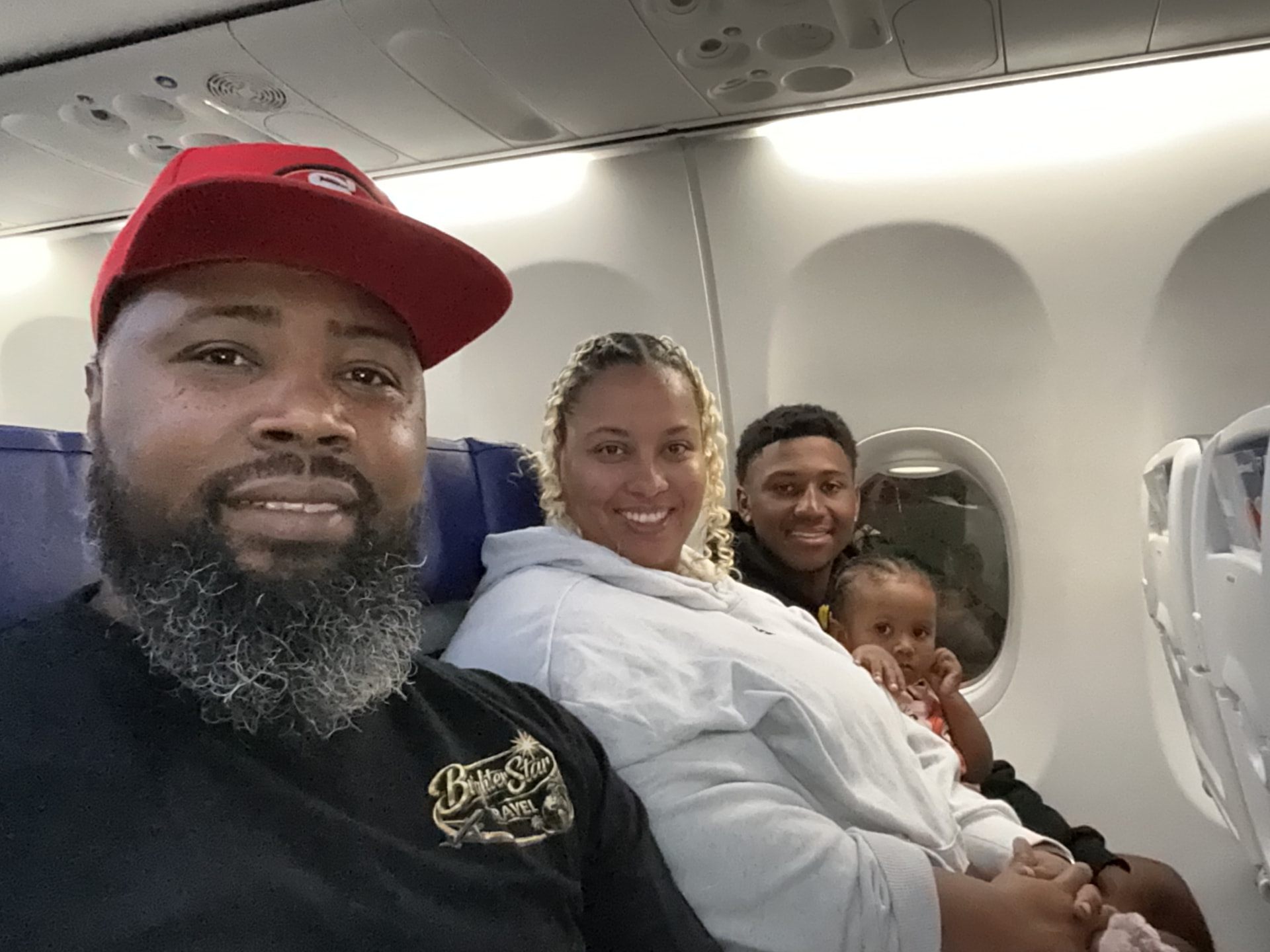 Joshua seated with his family inside an airplane cabin