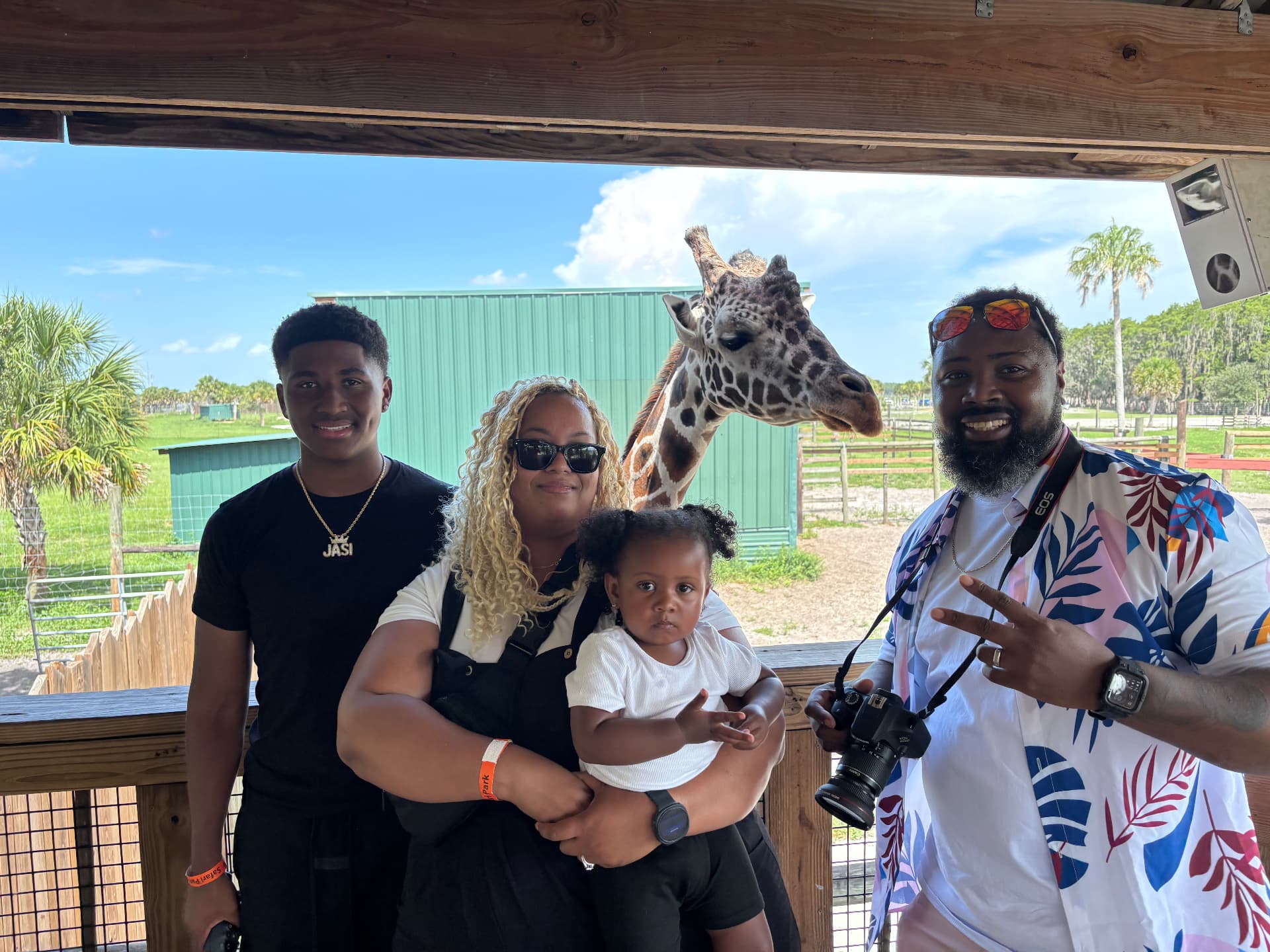 Joshua with his family beside a giraffe during a trip